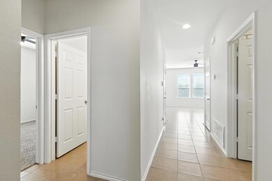 Hall with light tile patterned flooring and baseb