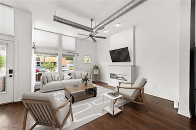 Virtually staged Living room with a towering ceiling, ceiling fan, a tiled fireplace, and dark hardwood / wood-style flooring