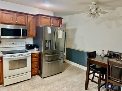 Kitchen featuring stainless steel appliances, light countertops, brown cabinets, light floors, and ceiling fan