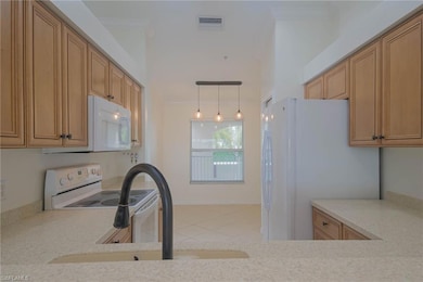 Kitchen featuring white appliances, crown molding, tile patterned floors, light countertops, and hanging light fixtures