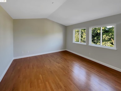 Unfurnished room featuring dark wood-style flooring and lofted ceiling