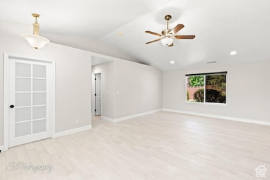 Spare room with light wood-style flooring, vaulted ceiling, a ceiling fan, and recessed lighting
