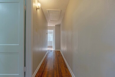 Hall with a textured ceiling, attic access, basebo