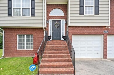 Entrance to property featuring concrete driveway, a garage, and brick siding