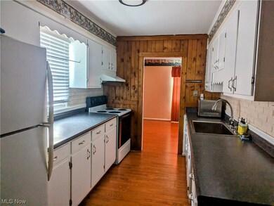 Kitchen featuring sink, light hardwood / wood-style floors, stainless steel fridge, electric stove, and white cabinetry