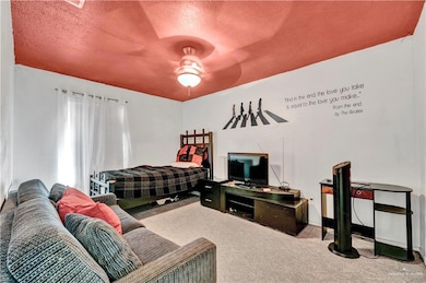 Carpeted bedroom with a textured ceiling, ceiling fan, and baseboards