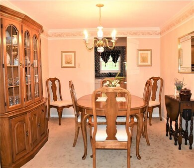 Formal dining room with crown molding and neutral decor.