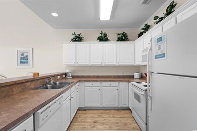 Kitchen featuring white appliances, white cabinets, ornamental molding, light wood-style flooring, and recessed lighting