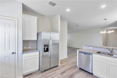 Kitchen featuring stainless steel appliances, light stone counters, hanging light fixtures, light wood-style flooring, and recessed lighting