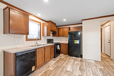 Modern kitchen with HW-Caramel cabinetry, full black appliance suite, and ample counter space