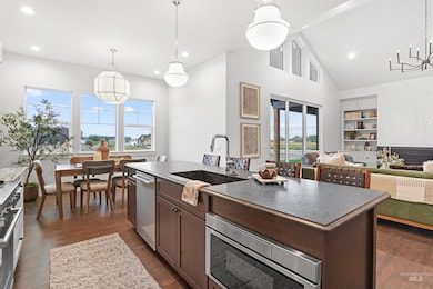 Kitchen featuring hanging light fixtures, an island with sink, dark wood finished floors, high vaulted ceiling, and dark brown cabinetry