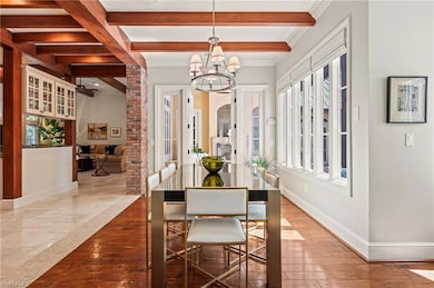 Dining area with chandelier, beamed ceiling, baseboards, ornamental molding, walnut floors, French door.