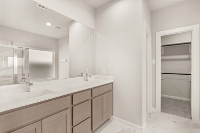 This primary bathroom is definitely move-in ready! Featuring light stained cabinets with light countertops, spacious walk-in closet with shelving, high ceilings, custom paint, sleek and dark modern finishes.

