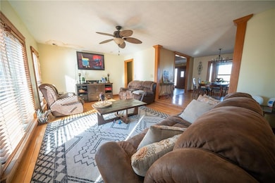 Living room featuring a textured ceiling, light hardwood / wood-style floors, and ceiling fan with notable chandelier