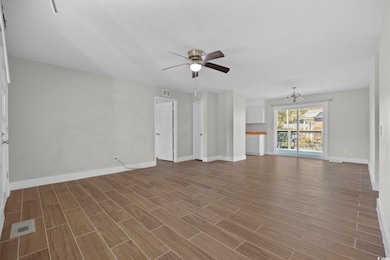 Unfurnished living room with a chandelier, a ceiling fan, and wood finish floors