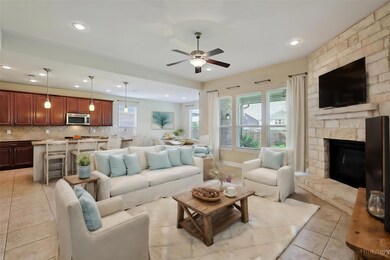 Living room featuring a stone fireplace, ceiling f