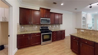 Kitchen with decorative backsplash, visible vents, stainless steel appliances, and light wood-style floors