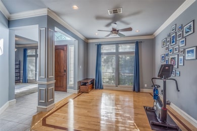Exercise room featuring crown molding, light wood-type flooring, ceiling fan, decorative columns, and recessed lighting