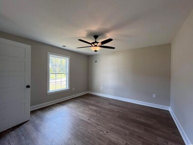 Unfurnished room featuring ceiling fan and dark ha