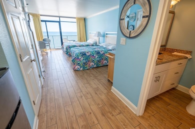 Bedroom featuring expansive windows, light wood-type flooring, access to exterior, a water view, and crown molding