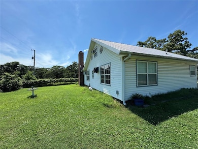View of side of home featuring a lawn, a metal roof, and a chimney
