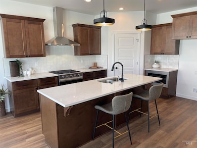 Kitchen featuring wall chimney exhaust hood, a breakfast bar, light stone counters, appliances with stainless steel finishes, and decorative backsplash