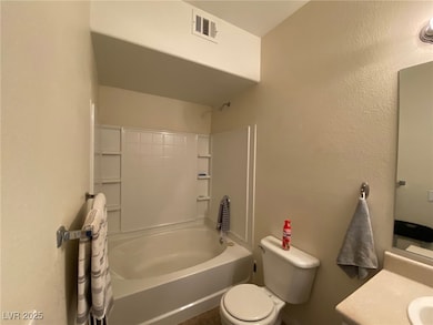 Full bathroom with vanity, toilet, visible vents, a textured wall, and shower / washtub combination