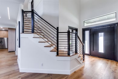Entryway featuring light wood-type flooring, a towering ceiling, and stairway