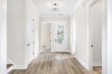 Entryway featuring crown molding and light hardwoo
