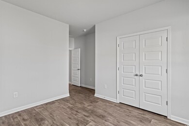 Unfurnished bedroom featuring wood finished floors, a closet, and baseboards