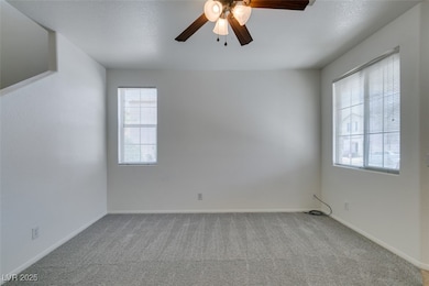Carpeted spare room featuring ceiling fan, plenty