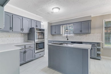 Kitchen with a center island, gray cabinets, tasteful backsplash, a textured ceiling, and stainless steel double oven