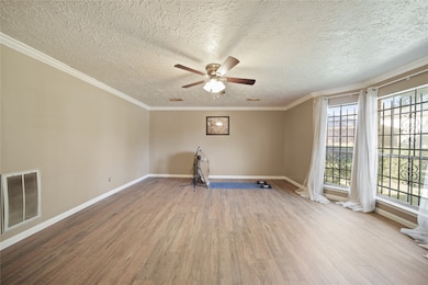 Bright and spacious living room with large windows, elegant flooring, neutral walls, and a ceiling fan, perfect for relaxation or entertaining.
