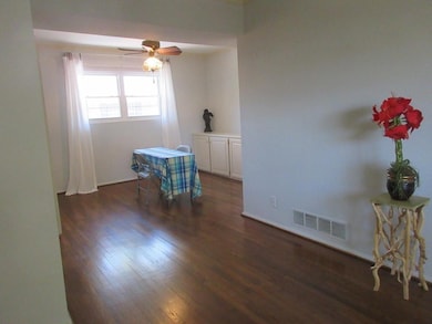 Unfurnished room featuring visible vents, dark woo