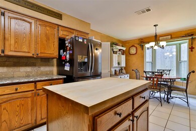 Kitchen featuring stainless steel fridge, tasteful backsplash, light tile flooring, an inviting view, and hanging light fixtures.