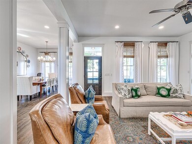Living room with ornate columns, wood-type flooring, and ceiling fan with notable chandelier