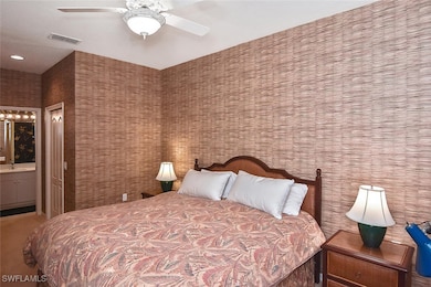 Carpeted bedroom with ensuite bathroom and ceiling fan
