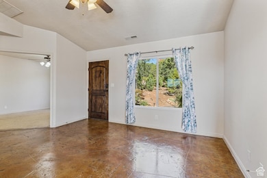 Unfurnished room featuring a ceiling fan, a textured ceiling, concrete floors, and lofted ceiling