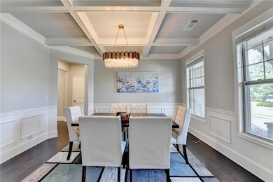 Dining room featuring a chandelier, dark wood-style flooring, beam ceiling, coffered ceiling, and a wainscoted wall