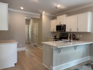 Kitchen featuring appliances with stainless steel finishes, a sink, a peninsula, a breakfast bar area, and light countertops