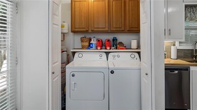 Washroom featuring cabinet space, washing machine and dryer, and water heater