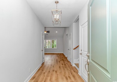 Hallway featuring a chandelier, light wood finished floors, and baseboards