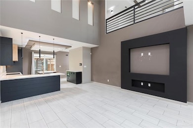 Unfurnished living room with baseboards and a towering ceiling