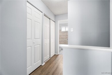 Hallway with hardwood / wood-style floors and a textured ceiling