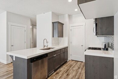 Kitchen featuring appliances with stainless steel finishes, light wood finished floors, recessed lighting, dark brown cabinets, and a peninsula