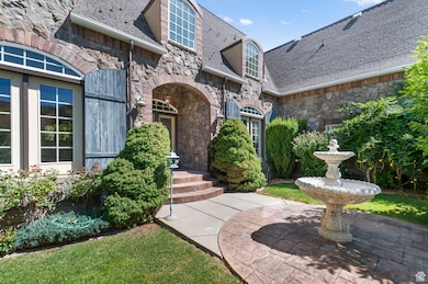Property entrance with stone siding, a patio area, and a shingled roof