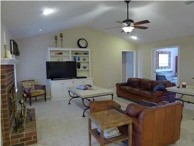 Great room with vaulted ceilings, carpet in center, tile around the edges for minimum wear, and a wood burning fireplace.