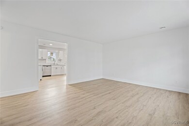 Empty room with baseboards, a sink, and light wood