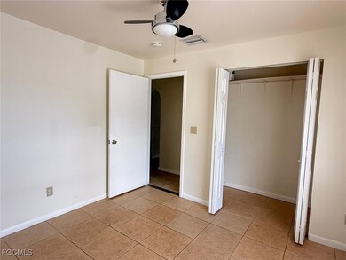 Unfurnished bedroom with light tile patterned floors, a ceiling fan, a closet, and arched walkways