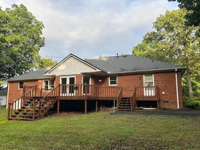Rear view of property featuring stairs, brick siding, and a yard